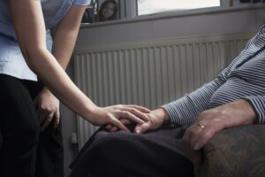 Personal care assistant comforting senior woman