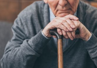 cropped view of upset retired man with walking cane